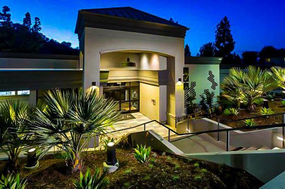Landscaped entryway with poured concrete steps surrounded by small palms and agave plants on a well-lit nighttime pathway