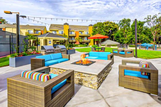 Southern California residential amenity with elevated fire pit, string lights, large planters, and two built-in grills