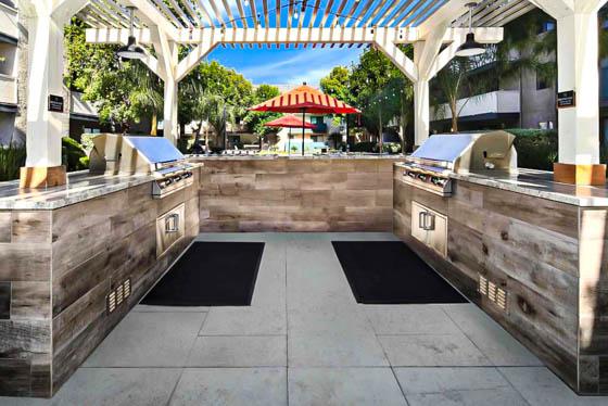 Adjacent grills covered by a white arbor to provide shade from the Orange County sunshine