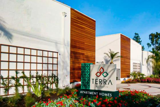 Flowerbeds with red flowers and trellaced plants at entryway with wood cladding in residential Tustin, California