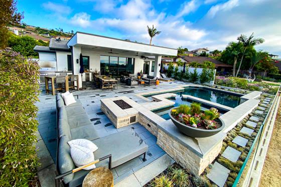 Outdoor spa and glowing firepit with cushioned deck furniture and accent lighting